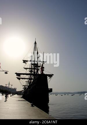 Replica della nave Victoria una carrack e la prima nave a circumnavigare il globo ormeggiato a Santander con forte luce solare del mattino attraverso l'opacità Foto Stock