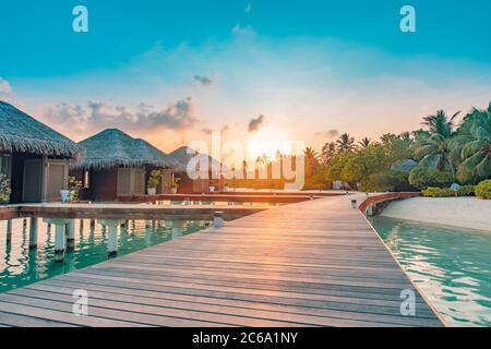 Tramonto sull'isola delle Maldive, resort di lusso con ville d'acqua e molo in legno. Belle nuvole di cielo e sfondo spiaggia per vacanze estive viaggio Foto Stock