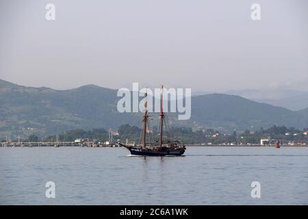 L'alta nave Atyla che si dirige verso il mare dalla baia di Santander alla luce del sole del mattino Foto Stock