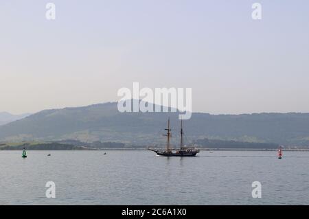 L'alta nave Atyla che si dirige verso il mare dalla baia di Santander alla luce del sole del mattino Foto Stock