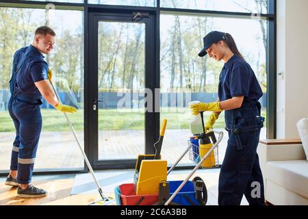 Due janitors casa di campagna pulita con finestra panoramica, lavaggi pavimenti. Vista laterale sul processo di lavorazione Foto Stock