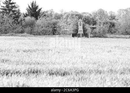 Antico santuario lungo il tragitto in campagna lucidata, tra campi di segale, immagine a infrarossi in bianco e nero Foto Stock