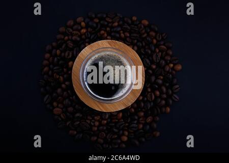 Diversi tipi di caffè e abbastanza varietà sullo sfondo nero nella vista dall'alto che viene versato sulla tavola di legno. Foto Stock