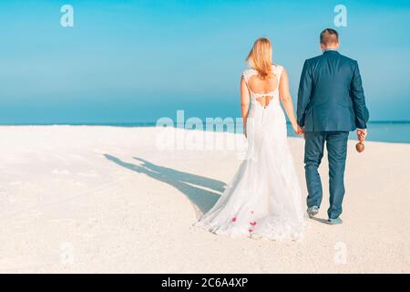 Appena sposato coppia camminando sulla spiaggia tropicale. Destinazione esotica per matrimoni. Matrimonio romantico coppia sulla spiaggia Foto Stock