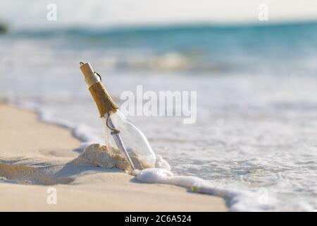Bottiglia con un messaggio, onde di mare che spruzzi sulla costa calma, riva. Concetto esotico di castaway. Flacone con un messaggio di aiuto. Spiaggia di mare. Foto Stock