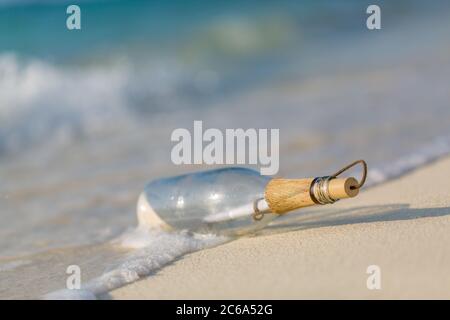 Bottiglia con un messaggio, onde di mare che spruzzi sulla costa calma, riva. Concetto esotico di castaway. Flacone con un messaggio di aiuto. Spiaggia di mare. Foto Stock