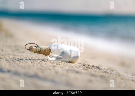 Bottiglia con un messaggio, onde di mare che spruzzi sulla costa calma, riva. Concetto esotico di castaway. Flacone con un messaggio di aiuto. Spiaggia di mare. Foto Stock
