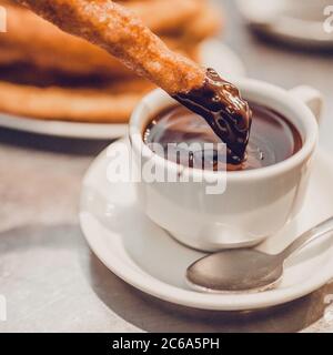 Gli spagnoli decisero di immergere i churros in una tazza di cioccolata calda - fuoco selettivo Foto Stock