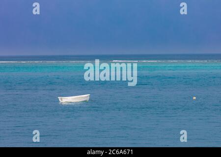 Piccola barca da pesca che galleggia sul mare blu. Barca di legno solitario, tranquillità e concetto di castaway Foto Stock