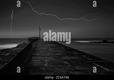 Molo di Porthleven Cornwall con mare tempestoso e fulmini Foto Stock