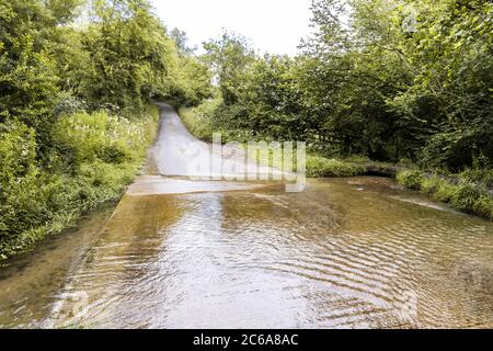 Il fiume Windrush infant che forge Critchford Lane vicino al villaggio di Cotswold di Guiting Power, Gloucestershire UK Foto Stock