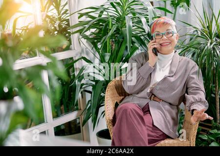 Personale anziana signora siede parlando su smartphone, sorridere e ridere. Buon lavoro, pausa tempo. Padrone di signora maturo Foto Stock
