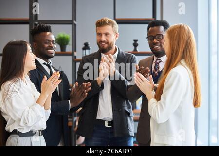 Giovani colleghi caucasici e africani si sono aggrappati dopo il lavoro di squadra in carica, la fine positiva del lavoro, festeggiando Foto Stock