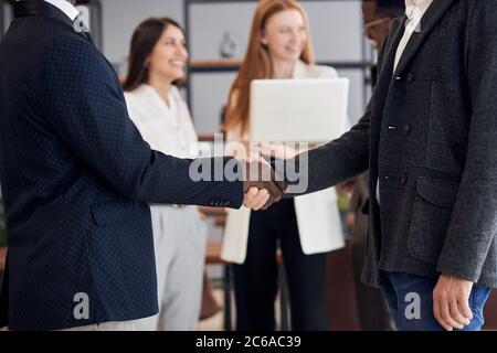 closeup afroamericano e caucasico dopo l'incontro di affari interracial scuotono le mani. Conclusione positiva e felice dei negoziati Foto Stock