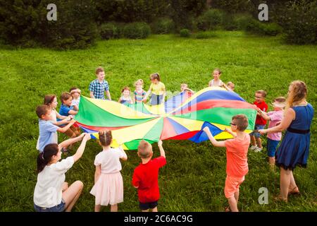 Giochi all'aperto con paracadute colorato. Campo estivo Foto Stock