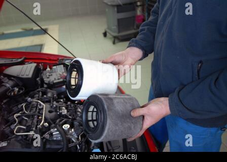 Riparatore che tiene un filtro dell'aria vecchio e uno nuovo Foto Stock