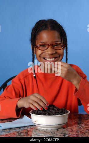 Austin, Texas USA, dicembre 2003: Bambina afroamericana di 10 anni che mangia uvetta a casa. SIGNOR ©Bob Daemmrich Foto Stock