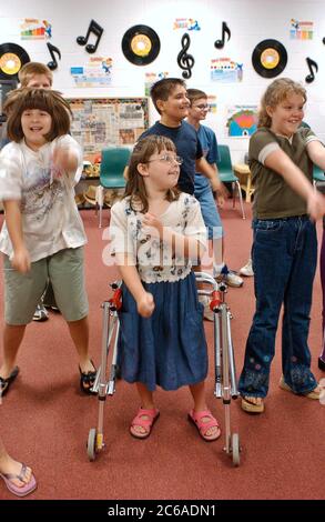 Gun Barrel City, Texas 9 settembre 2003: Una ragazza fisicamente handicappata con paralisi cerebrale che usa un camminatore balla con i suoi compagni di quinta elementare durante la lezione di apprezzamento della musica. La scuola integra i suoi studenti disabili, collocandoli con studenti normalmente disabili in tutti gli ambienti scolastici. RILASCIO MODELLO SP70 (ragazza con scuotipaglia), altri non rilasciati. ©Bob Daemmrich Foto Stock