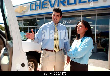 Austin, Texas USA, 20 agosto 2003: Il giovane venditore di auto ispaniche aiuta la donna ispanica a comprare una nuova auto presso una concessionaria Chevrolet GM sul "Motor Mile" di Austin sud. Con l'economia in agguato, i venditori stanno trovando difficile attirare gli acquirenti su nuovi veicoli quest'estate. SIGNOR ©Bob Daemmrich Foto Stock