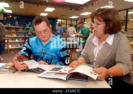 Mabank, Texas: 10 settembre 2003: Ragazzo tredicenne con sindrome di Down nella sua biblioteca della scuola media, che guarda libri e interagisce con uno specialista del discorso e dell'udito. SIG. SP75 (ragazzo in blu) SP69 (adulto) ©Bob Daemmrich Foto Stock