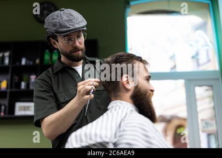 Il soggiorno al barbiere è stato fantastico. Ci sono un parrucchiere e un giornale mentre ci si siede in poltrona al barbiere Foto Stock