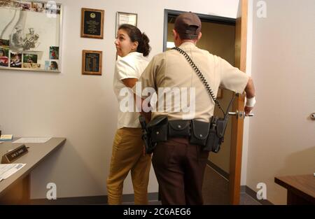 Austin, Texas USA, 28 agosto 2003: Una donna ispanica in libertà vigilata che ha violato i termini della sua libertà vigilata ordinata dal tribunale viene arrestata nell'ufficio del suo ufficiale di libertà vigilata dopo aver fallito un test di abuso di sostanze. Modelli rilasciati. ©Bob Daemmrich Foto Stock