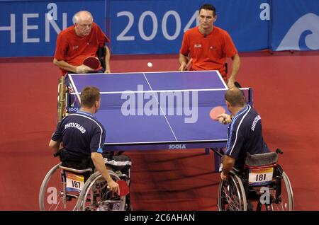 Atene, Grecia 23SEP04: Rolf Zumkehr (camicia rossa con capelli bianchi) e Christian Sutter (255) combattono Werner Burkhardt (181) e Dietmar Kober (187) in Germania nella partita di tennis da tavolo maschile di classe 4. ©Bob Daemmrich Foto Stock