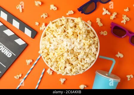 Composizione con secchio di popcorn su sfondo arancione. Cibo per guardare il cinema Foto Stock