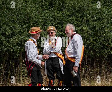 Tre ballerini Morris chiacchierano bevendo e socializzano tra le danze. Warwickshire Inghilterra Regno Unito Foto Stock