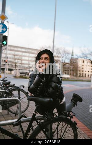 Giovane donna che si posa in un parcheggio con biciclette Foto Stock