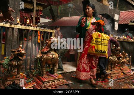 Donna nepalese lascia il santuario principale nel tempio di Dakshinkali vicino a Kathmandu, Nepal. Uno dei templi indù più importanti del Nepal dedicato alla dea Kali è noto per i suoi sacrifici animali che si svolgono nel santuario principale. Foto Stock