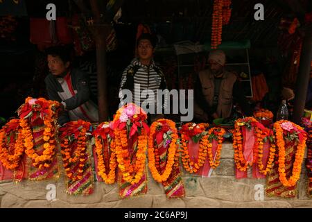 Venditori ambulanti vendono ghirlande di fiori marigold per rituale puja sul percorso al tempio di Dakshinkali vicino a Kathmandu, Nepal. Uno dei templi indù più importanti del Nepal dedicato alla dea Kali è noto per i suoi sacrifici animali. Foto Stock