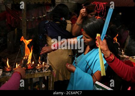 Donne nepalesi hanno illuminato i bastoni di incenso dalle lampade ad olio rituali nel santuario principale del tempio di Dakshinkali vicino a Kathmandu, Nepal. Uno dei templi indù più importanti del Nepal dedicato alla dea Kali è noto per i suoi sacrifici animali che si svolgono nel santuario principale. Foto Stock