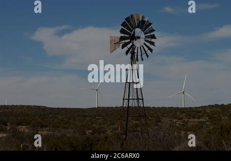 Iraan, Texas USA, 18 febbraio 2004: Un mulino a vento vecchio stile si trova di fronte alle moderne turbine eoliche presso la Desert Sky Wind Farm su una mesa nell'estremo ovest del Texas fornisce elettricità per la rete elettrica per alimentare migliaia di case. ©Bob Daemmrich Foto Stock