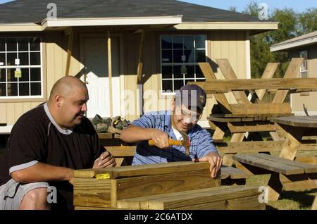 San Juan, Texas USA, 17 dicembre 2004: Padre ispanico e figlio di 15 anni si offrono volontari per lavorare sulle scale per una nuova casa in un progetto di alloggi a basso reddito. La famiglia acquistò una casa attraverso Proyecto Azteca, un programma di assistenza abitativa in cui le famiglie contribuiscono ore di volontariato in cambio dell'aiuto di Proyecto Azteca nel finanziamento dell'acquisto di una casa. Modello rilasciato. ©Bob Daemmrich Foto Stock