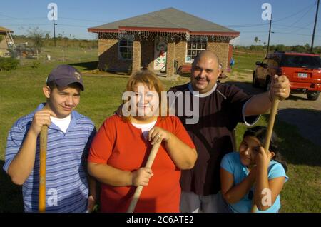 Monte alto, Texas USA, 11 dicembre 2004: La famiglia Villalpando posa davanti alla loro modesta casa con tre camere da letto, un bagno finanziato da Proyecto Azteca, un programma di assistenza abitativa che richiede alle famiglie di contribuire volontariato in cambio dell'acquisto di una casa a basso costo. Modello rilasciato ©Bob Daemmrich Foto Stock