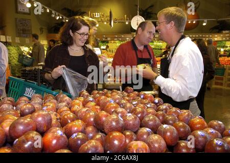 Austin, Texas USA, 3 marzo 2005: Una donna che acquista parla per produrre un dipendente del reparto in una mostra di mele fresche durante l'inaugurazione del flagship store di 80.000 metri quadrati di Whole Foods e della sede centrale dell'azienda nell'Emerging Market District di Austin. La catena nazionale ha 167 negozi ed è il principale supermercato naturale e biologico al mondo. ©Bob Daemmrich Foto Stock