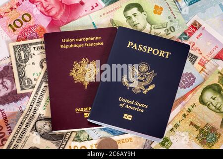 Passaporti degli Stati Uniti e della Francia circondati da valute internazionali. Foto concettuale per i ricchi turisti occidentali che spendono denaro. Foto Stock