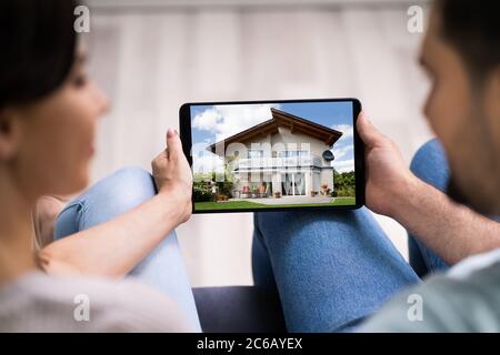 Famiglia di coppia che cerca bene immobile in linea sul tablet Foto Stock