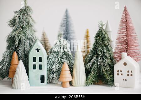 Case e alberi di Natale su sfondo bianco. Arredamento moderno e festoso. Buone vacanze. Piccolo villaggio accogliente, case in ceramica, legno e handma Foto Stock