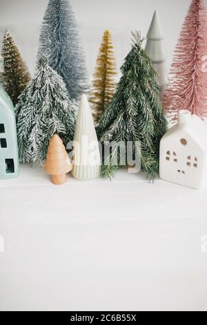 Buone vacanze. Piccolo villaggio accogliente, case in ceramica, legno e alberi di natale fatti a mano. Case e alberi di Natale su sfondo bianco. Fe Foto Stock