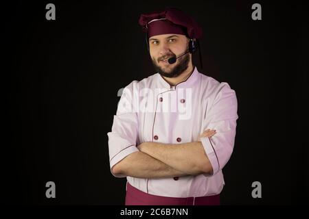 allegro sorridente giovane cuoco maschile bearded cuoco in uniforme che parla con la cuffia Foto Stock