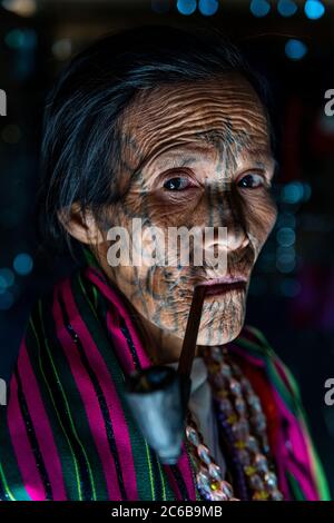 Donna di mento con tatuaggio spiderweb che fuma un tubo, Mindat, Stato di Chin, Myanmar (Birmania), Asia Foto Stock