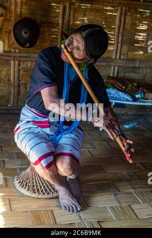 Donna di mento con tatuaggio spiderweb che soffia un flauto con il naso, Kanpelet, Chin stato, Myanmar (Birmania), Asia Foto Stock