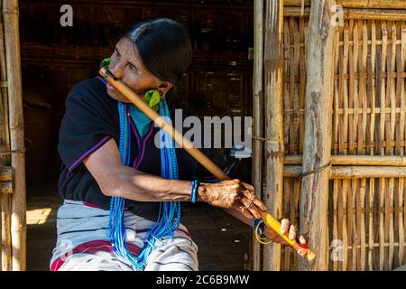 Donna di mento con tatuaggio spiderweb che soffia un flauto con il naso, Kanpelet, Chin stato, Myanmar (Birmania), Asia Foto Stock