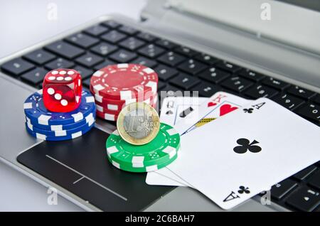 Carte da gioco, chip casinò e moneta euro su una tastiera per computer portatile simboleggiando il gioco d'azzardo online Foto Stock
