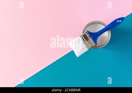 Lattina di vernice bianca con un pennello blu su sfondo colorato, pittura, vista dall'alto Foto Stock