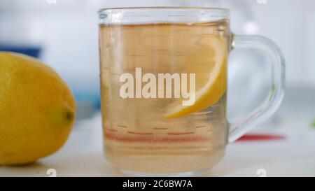 Tazza fresca dolce e calda con tè e una fetta di limone al mattino a colazione Foto Stock
