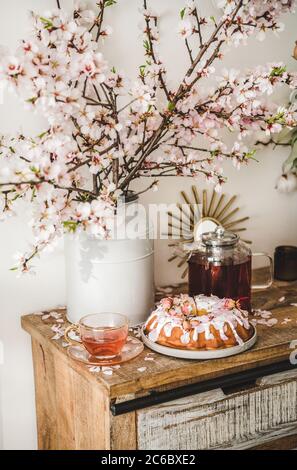 Torta senza glutine e tè sotto rami fiorenti di mandorle Foto Stock