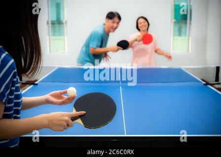 Divertimento di coppia giocando a ping pong o Ping pong al coperto insieme tempo libero con la competizione in giochi sportivi in casa. Padre madre e figlia famiglia asiatica Foto Stock